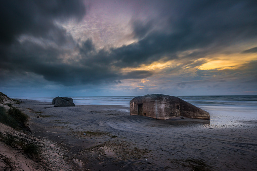 Skagen, Denmark - september 28 2014: Wartime bunkers slowly sinking into the sand in sunset light.