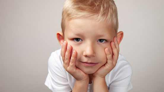 Studio portrait of a cheerful 5 year old boy on an beige background