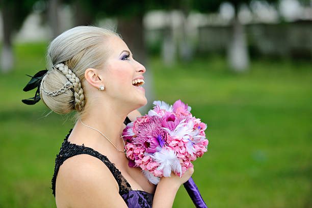 blond hair elegant woman with hairbun holding flower bouquet.