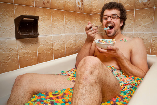 Funny man eating his cereals in the bathtub