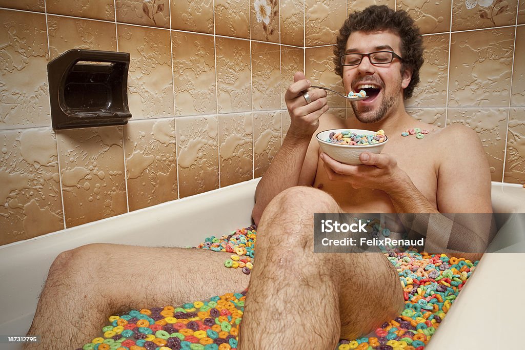 Funny man eating his cereals in the bath Funny man eating his cereals in the bathtub Bizarre Stock Photo