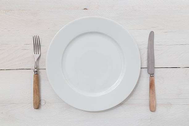 White plates and silverware on a light wood