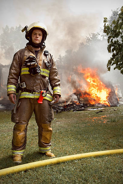 Real Firefighter with house on fire in background stock photo