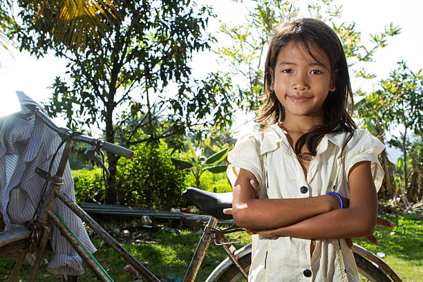 Portrait of young Asian (Cambodian) little girl posing near her old bicycle.