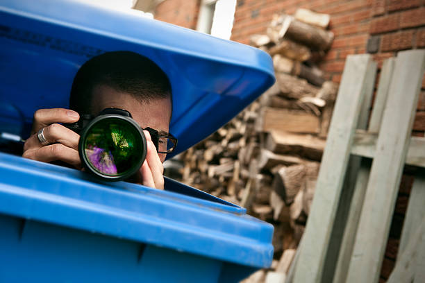 Paparazzi hiding in a blue garbage bin stock photo