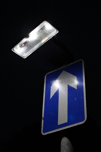 One way road sign at night with light to illuminate sign, dark background