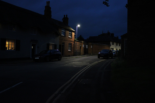 Dark village street taken at night, cars and houses visible, low light photo