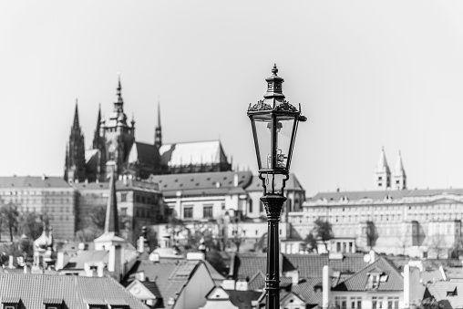 Vintage street lamp on Charles Bridge. Prague Castle out of focus on the background. Prague, Czech Republic. Black and white image.