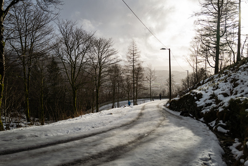 Bergen, Norway - February 1, 2023: People winter hiking at Fløyen on February 1, 2023 in Bergen, Norway. People walking carefully over ice and snow, on the major hill over Bergen.