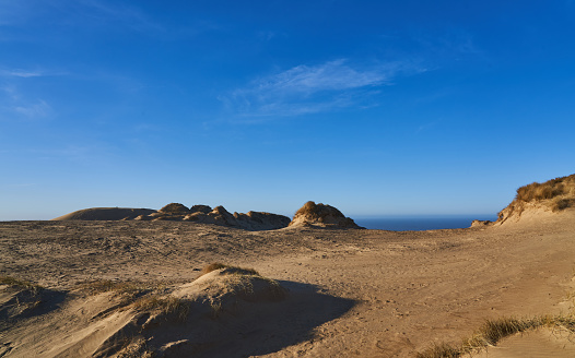 Idyllic scenic view of brown mountain with rocks and sand against blue sky during sunny day at Lønstrup, Denmark