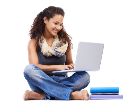 A beautiful young woman sitting on the floor and using a laptop against a white background