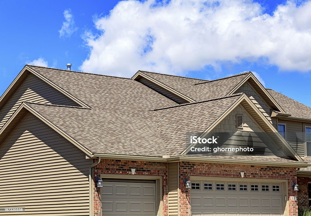 Asphalt roofing shingles on new home Photo of new asphalt shingles on a two story home. Blue sky and clouds are in the background. Rooftop Stock Photo