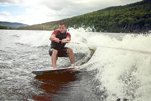 wakesurf felice bell'uomo in un lago - wakeboarding surfing men vacations foto e immagini stock