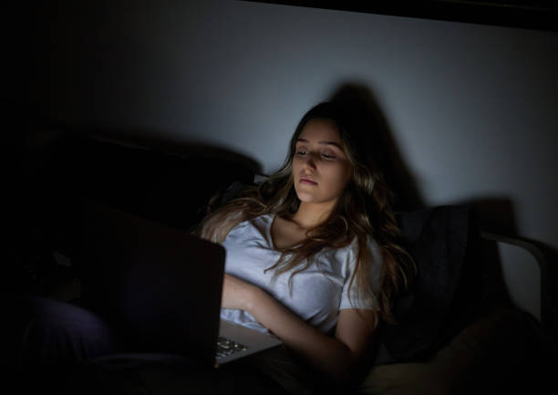 istock Woman concentrating on laptop computer on her bedroom bed 1873216422