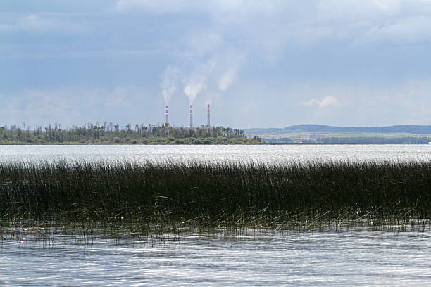 A beautiful lake may not be as pristine as it appears with three stacks from a coal powered plant spewing out smoke.