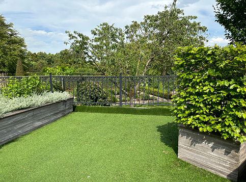 Artificial grass and wooden containers with plants in the roof garden