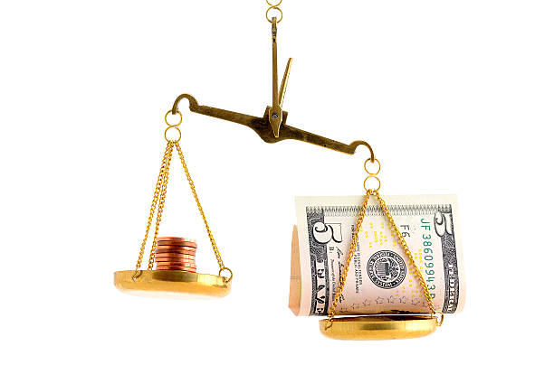 Imbalance betweeen dollar bill and copper coins on scale stock photo