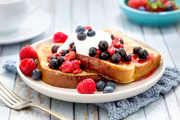 French Toast with Berries and Cream French toast topped with blueberries, raspberries, and cream. french toast stock pictures, royalty-free photos & images