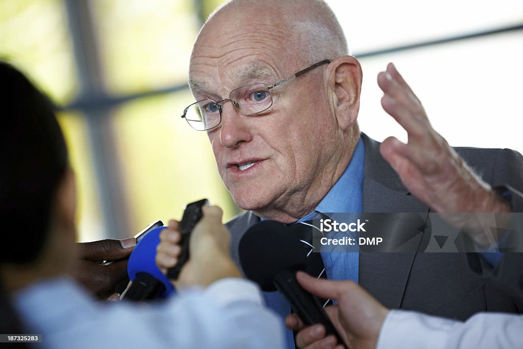 Hombre maduro responder a los periodistas executive - Foto de stock de 70-79 años libre de derechos