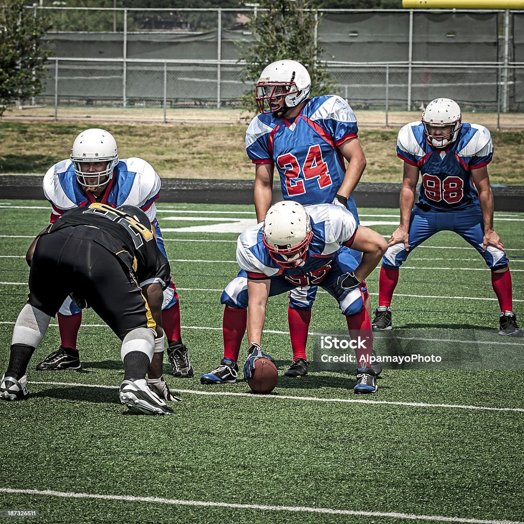 Football team prepares for the play - III Football players on the field during game preparing the start the play. Scrimmage game. American Football Player Stock Photo