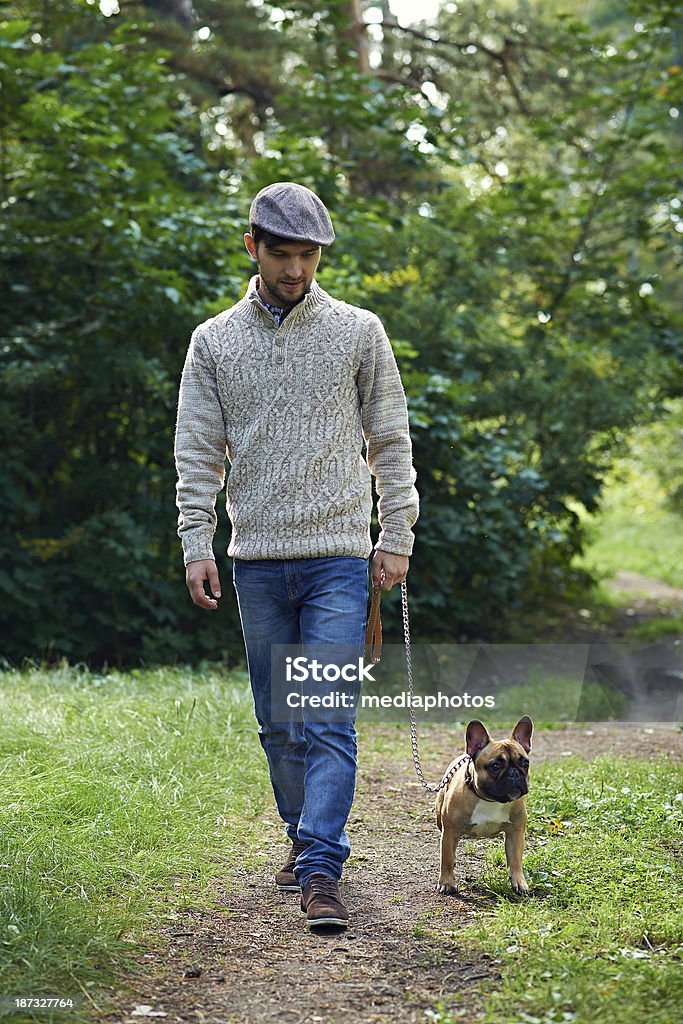 Stylish dog owner Stylish guy walking with his French bulldog in tree area Men Stock Photo