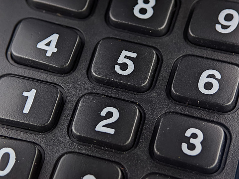 Close-up of number on a black calculator. Background and textured.