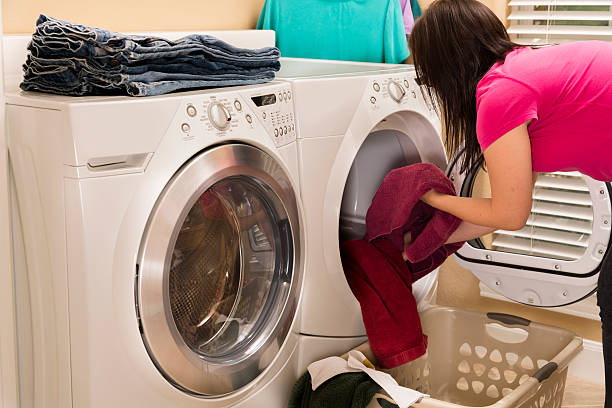 Woman removes laundry from new, energy-efficient clothes dryer.  Laundry room.