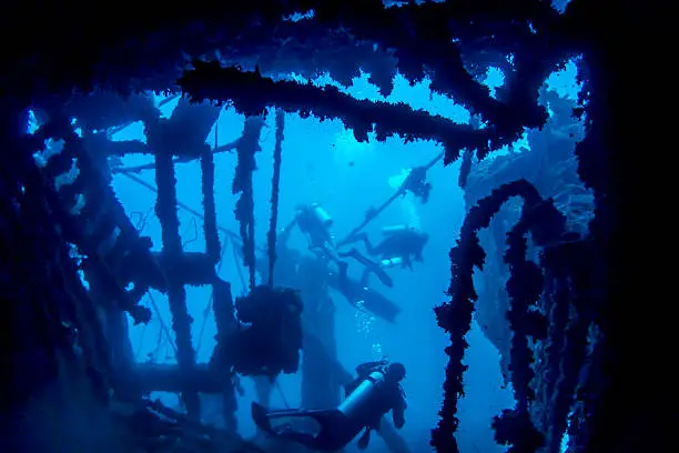 Scuba divers passing through inside of large Coolidge shipwreck in Vanuatu