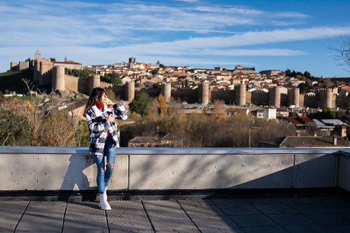 Brunette tourist in casual attire, marvels at Avila's scenic beauty from the overlook.