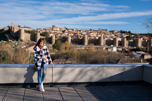 Casual traveler with checkered jacket enjoys the stunning panorama of Avila historic fortifications