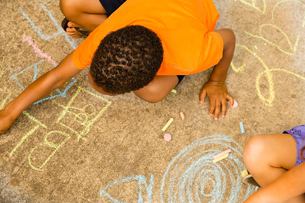 niños: grupo multiétnico jugando con tiza en la acera. - little girls sidewalk child chalk fotografías e imágenes de stock