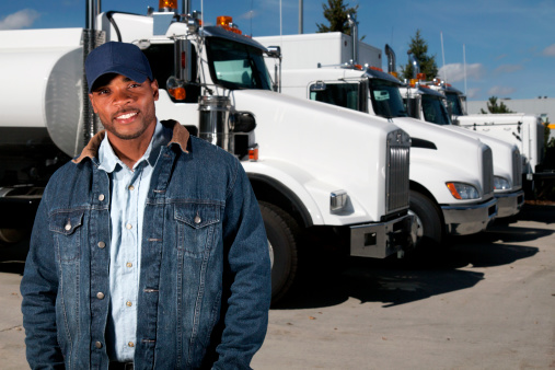 A royalty free image from the trucking industry of a friendly truck driver in front of a semi truck.