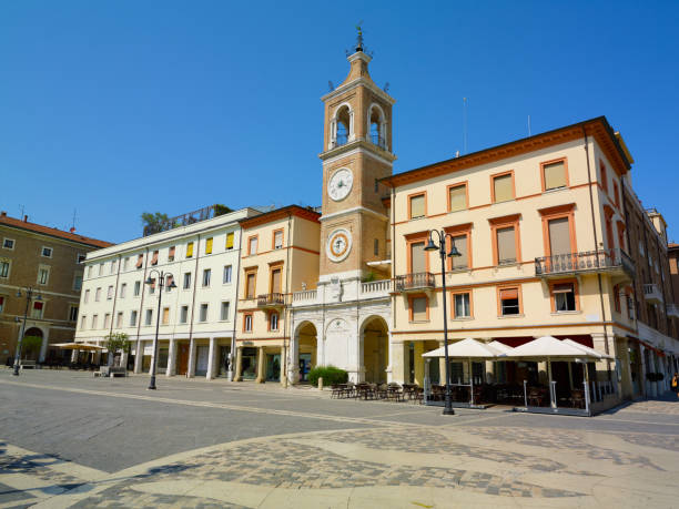 istock Piazza Tre Martiri Three Martyrs square with traditional buildings with clock and bell tower in old historical touristic city centre Rimini with blue sky background, Emilia-Romagna, Italy 1873380321