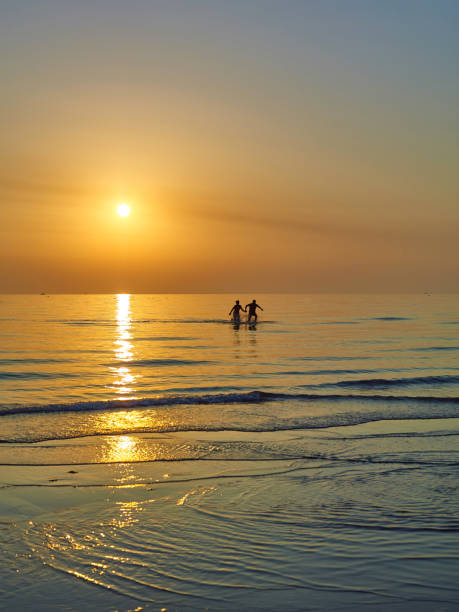 istock Couple are walking along the sunset beach 1873381903