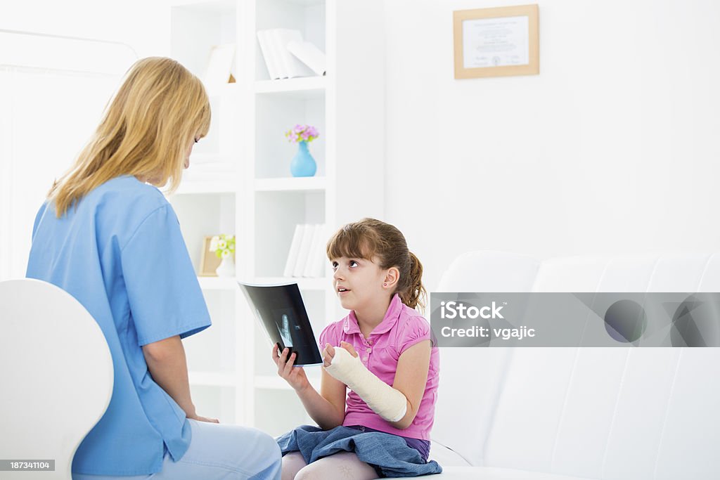 Girl With Broken Arm at Doctors Office. Girl With Broken Arm at Doctors Office. Selective focus to little girl looking at x-ray image and doctor. 25-29 Years Stock Photo
