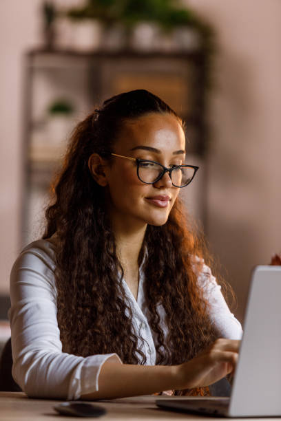 istock Young woman with eyeglasses working at her desk, using laptop 1873431839
