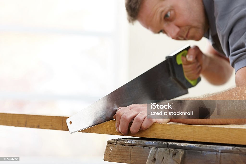 Madura carpenter de prancha de madeira com uma serra - Foto de stock de Madeira royalty-free