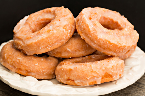 A close up shot of a white plate full of pumpkin doughnuts.