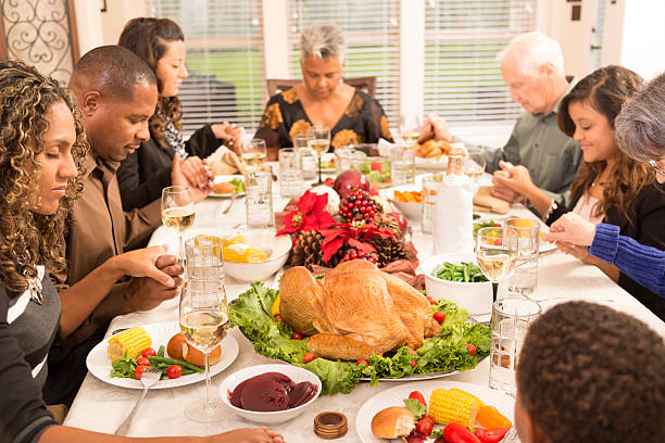 istock Christmas:  Family and friends pray before eating dinner. 187345178