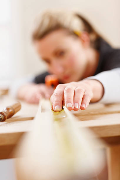 istock Female carpenter measuring wood at site 187345706