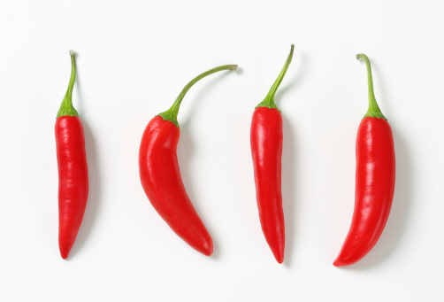 Fresh red chilli peppers and cross sections of chilli pepper with seeds floating in the air. File contains clipping paths.