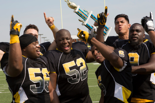 Football team enjoys a victory. This stock image has a horizontal composition and blue sky background. 