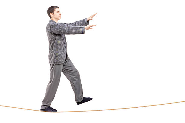 istock Young man in pajamas sleepwalking on a rope 187350018