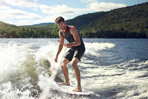 Happy handsome man wakesurfing in a lake stock photo
