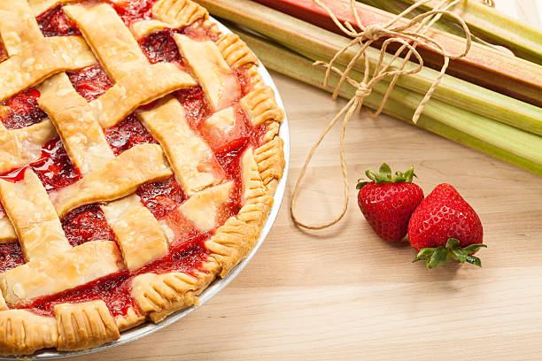 Strawberry Rhubarb Pie Homemade strawberry rhubarb pie with Strawberries and rhubarb on a wooden cutting board. Traditional late summer/early fall dessert. rhubarb photos stock pictures, royalty-free photos & images