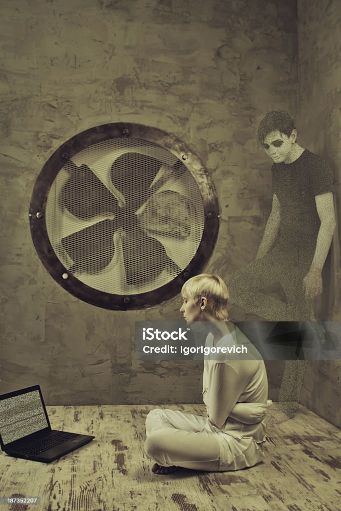 Noisy hallucination Sad girl in straitjacketsitting in a cell of an asylum. Hallucination stands behind her. Accidents and Disasters Stock Photo