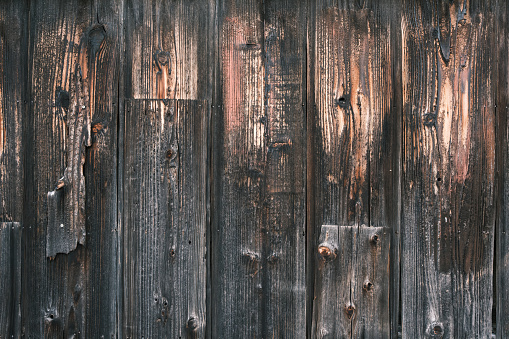 Section of a dark gray wooden fence with faded and peeling paint.