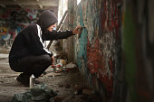 Illegal Young man Spraying paint on a Graffiti wall.