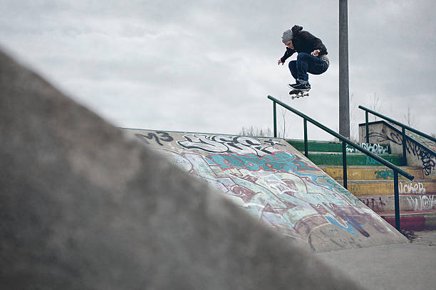 Skateboarder doing Ollie over the rail in a skatepark stock photo