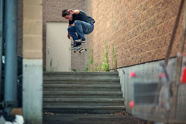 Skateboarder doing a Kickflip down the stairs stock photo